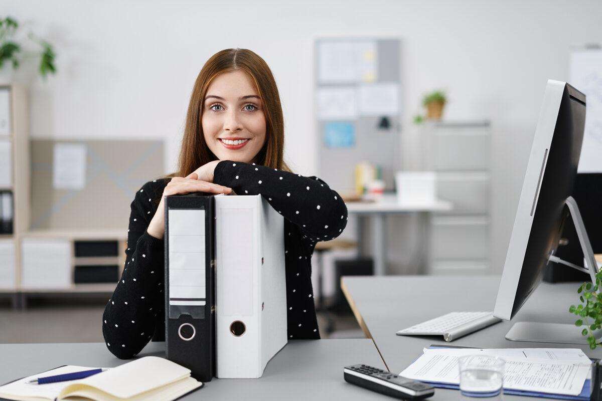 Lächelnde Frau Im Büro Stützt Sich Auf Aktenordner